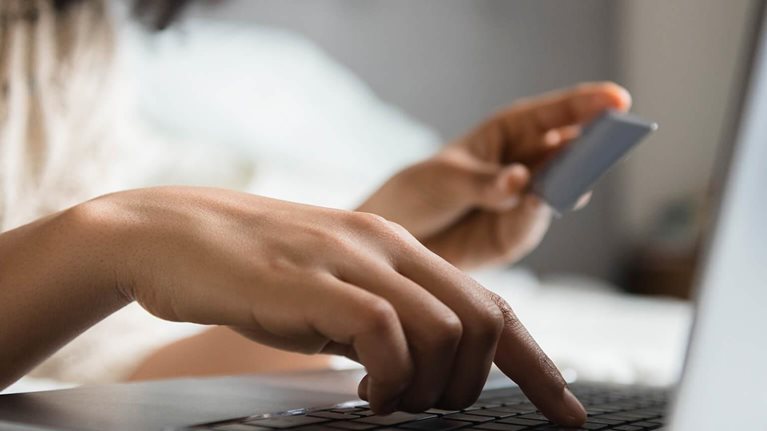 Woman laying in bed online shopping with laptop