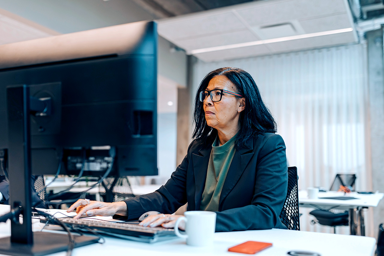 Confident businesswoman using a computer while sitting at her desk in her office.