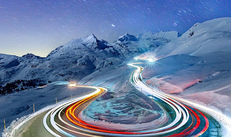 Car trail lights on snowy mountain road