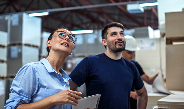 Image of a warehouse supervisor walking and talking with a senior manager while inspecting a warehouse.